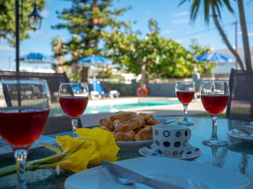 a table with glasses of wine and a plate of food at Spyros Villa Apartments in Adelianos Kampos
