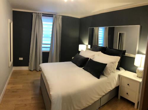ein Schlafzimmer mit einem großen Bett mit schwarzen und weißen Kissen in der Unterkunft GRAPHITE APARTMENTS in Inverness