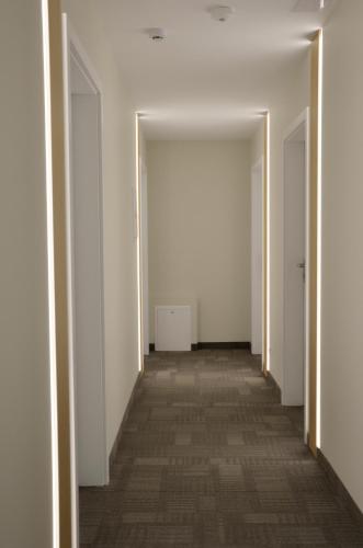 an empty corridor with white walls and a long hallway at Tip Tap Guest House in Druskininkai