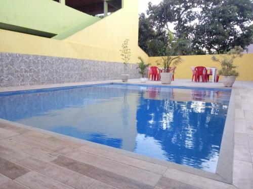 una piscina con sedie rosse accanto a un edificio di Guest House Renascer K&W a Cabo Frio
