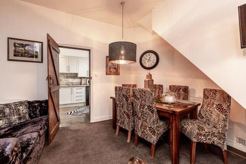 a dining room with a table and chairs and a clock at Quadrant Cottage in Buxton