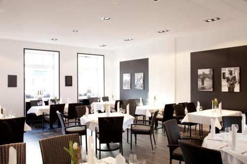 uma sala de jantar com mesas e cadeiras brancas em Hotel Restaurant Telgter Hof em Telgte
