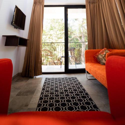a living room with an orange couch and a large window at HALF Hotel, Calangute in Calangute