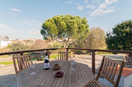 a wooden table with a bottle of wine and two glasses at Casa do Loureiro 1 - Seia - Serra da Estrela in Seia