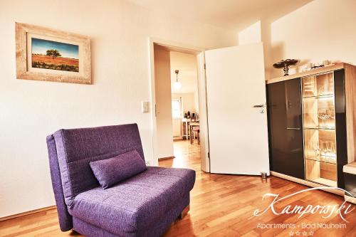 a living room with a purple chair and a kitchen at Kampowski Apartments Bad Nauheim in Bad Nauheim