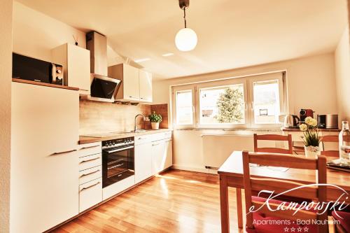 a kitchen with white cabinets and a table and a dining room at Kampowski Apartments Bad Nauheim in Bad Nauheim