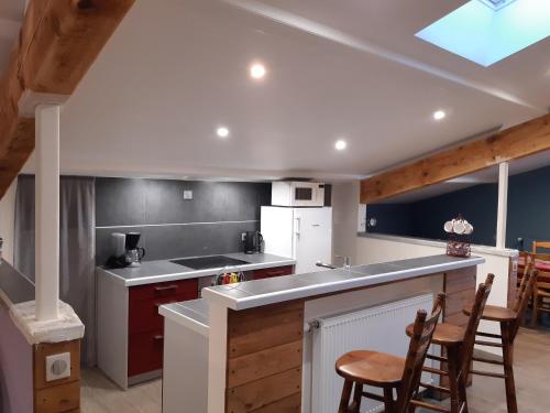 a kitchen with a sink and a counter with chairs at GITES LES MAISONS ROUGES in Jasseron