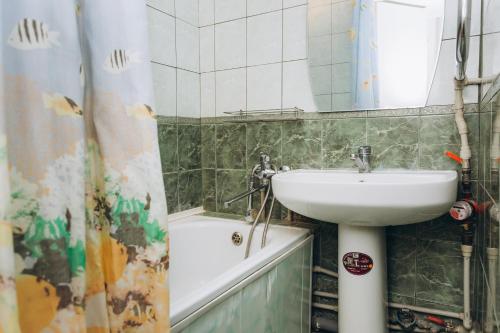 a bathroom with a sink and a mirror and a tub at Premium Home in Sumy