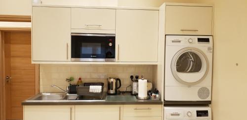 a kitchen with a sink and a washing machine at London Luxury Apartments 5 min walk from Ilford Station, with FREE PARKING FREE WIFI in Ilford