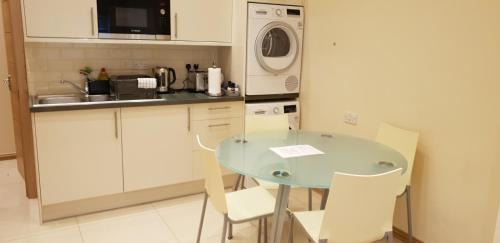 a kitchen with a table and chairs and a microwave at London Luxury Apartments 5 min walk from Ilford Station, with FREE PARKING FREE WIFI in Ilford