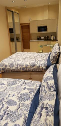 two beds in a room with a kitchen at London Luxury Apartments 5 min walk from Ilford Station, with FREE PARKING FREE WIFI in Ilford