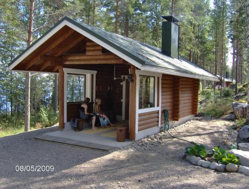 two people sitting in a cabin in the woods at KoliCarelia Cottages in Hattusaari