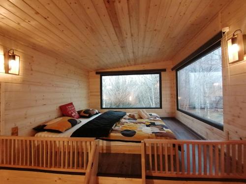 a bed in a log cabin with two windows at Piece of Heaven and Piece of Dream in Râşnov