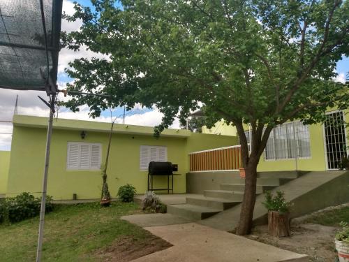 a yellow house with a tree in front of it at Atardecer Serrano in Huerta Grande