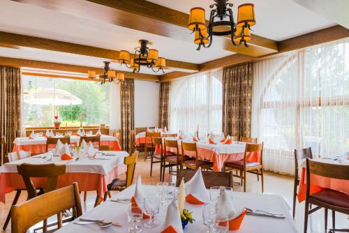 un restaurant avec des tables blanches, des chaises et des fenêtres dans l'établissement Hotel Buchholz, à Salorno