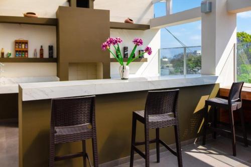 a kitchen with three bar stools and a counter with purple flowers at El Angolo in Lima