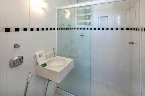 a white bathroom with a sink and a shower at Studio frente mar no Leme para 2 pessoas in Rio de Janeiro