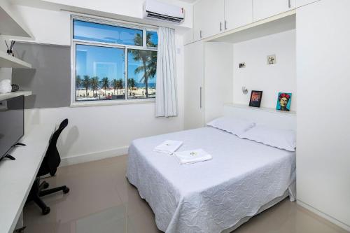 Schlafzimmer mit einem Bett, einem Schreibtisch und einem Fenster in der Unterkunft Studio frente mar no Leme para 2 pessoas in Rio de Janeiro