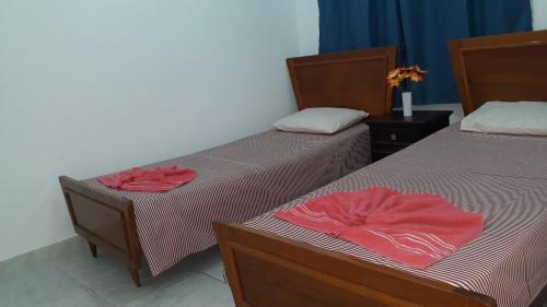 2 Betten in einem Zimmer mit roter Bettwäsche in der Unterkunft Sua Casa na Praia da Costa 10 Esta Tem Ar Condicionado Internet 2Q Completa Geladeira Fogao TV Centro in Vila Velha
