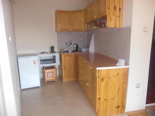 cocina con armarios de madera y nevera blanca en Guest House Antoaneta en Nesebar