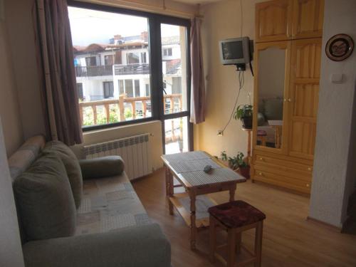 ein Wohnzimmer mit einem Sofa, einem Tisch und einem Fenster in der Unterkunft Guest House Antoaneta in Nessebar
