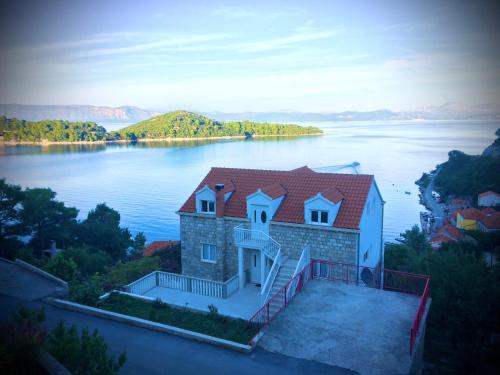 a house on the edge of a body of water at Guest House Ruža in Sobra
