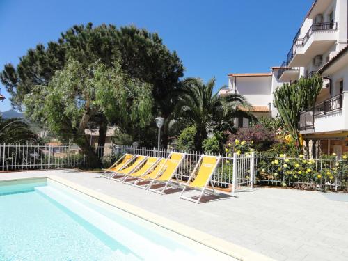 a group of yellow lounge chairs next to a swimming pool at Residence Dei Fiori in Pietra Ligure