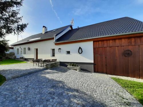 a house with a wooden garage and a stone driveway at Chalupa Chlum Míša in Volary