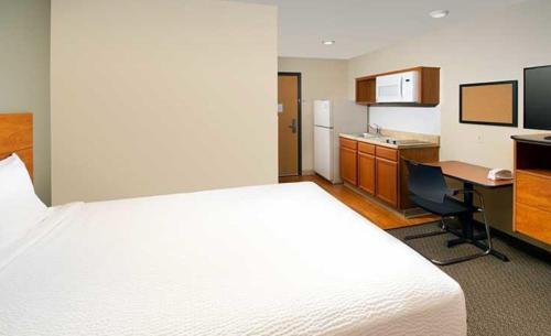 a hotel room with a bed and a desk and a kitchen at WoodSpring Suites Dallas Rockwall in Rockwall