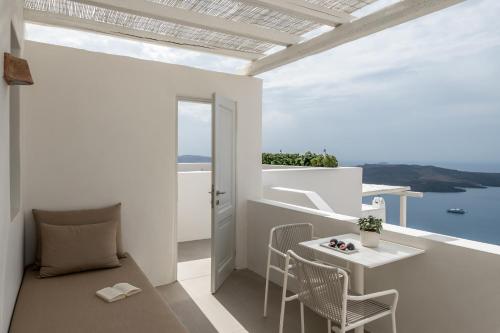 a room with a balcony with a table and chairs at Enigma Suites in Fira