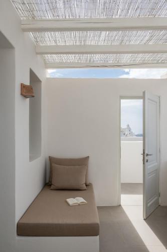 a bed in a white room with a ceiling at Enigma Suites in Fira