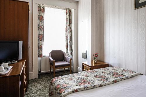 Habitación de hotel con cama, silla y ventana en The Columbia en Londres