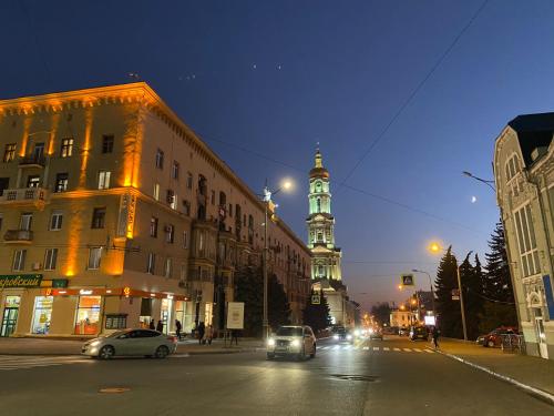 a city street at night with a clock tower at New luxury Apartment in the Center on Konstitution Square in Kharkiv
