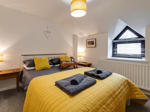 a bedroom with a yellow bed with two towels on it at 2 Ysgoldy in Bangor