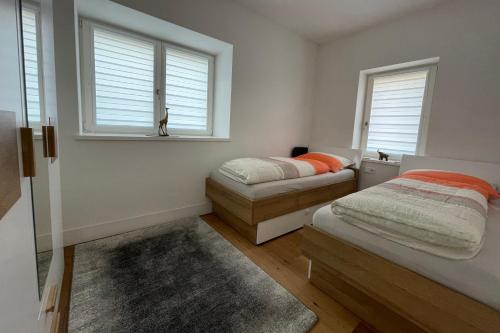 a bedroom with two beds and two windows at Apartments Griesser in Bressanone