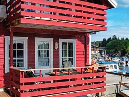 a woman sitting on the porch of a red house at 6 person holiday home in HOSTELAND in Hosteland