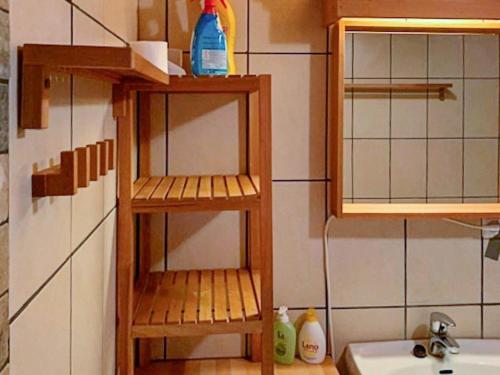 a small kitchen with wooden shelves next to a sink at 6 person holiday home in HOSTELAND in Hosteland