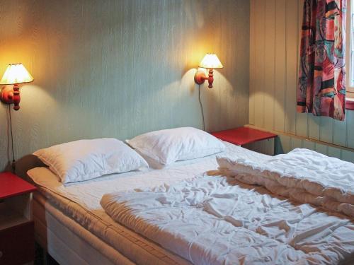 a bed in a room with two lamps on the wall at 6 person holiday home in HOSTELAND in Hosteland