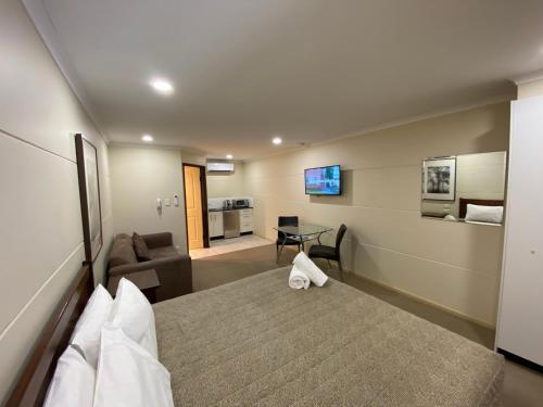 a hotel room with a bed and a living room at Balranald Club Motel in Balranald