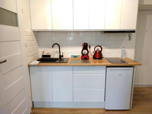 une cuisine avec des armoires blanches et une bouilloire sur un comptoir dans l'établissement theApartments Radwańska, à Łódź