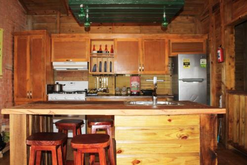 a kitchen with wooden cabinets and a counter with stools at Estancias Arroyazo in Constanza