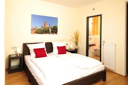 um quarto com uma grande cama branca com almofadas vermelhas em GuestHouse Mainz em Mainz