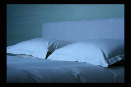 a bed with white sheets and pillows in a room at B&B AubergInn in Tessenderlo