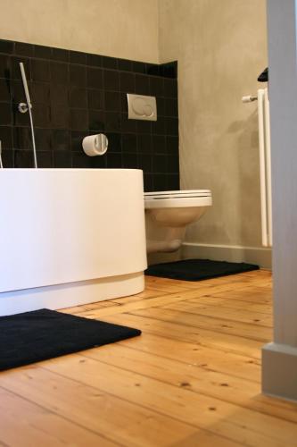 a bathroom with a toilet and a shower and a wooden floor at B&B AubergInn in Tessenderlo