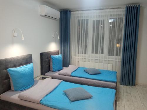 dwa łóżka w pokoju z oknem w obiekcie Апартаменты Weekend Inn w mieście Użhorod