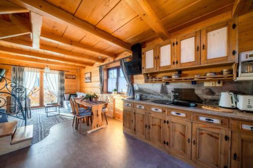a kitchen with wooden cabinets and a table in a room at Domki Widokowe Wooden Luxury Chalet with Private Jacuzzi in Ząb