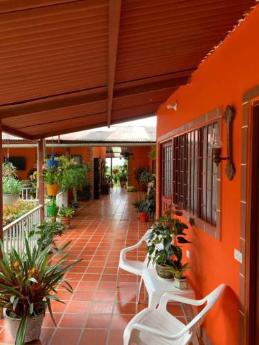 an orange building with chairs and potted plants at Finca campestre en Mesitas del Colegio in La María