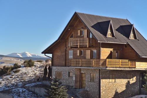a large wooden house with a gambrel roof at Kiwi Chalet in Kupres
