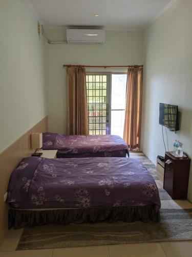 1 dormitorio con 2 camas y ventana en 屏東的家 en Ho-p'ing-hsin-ts'un