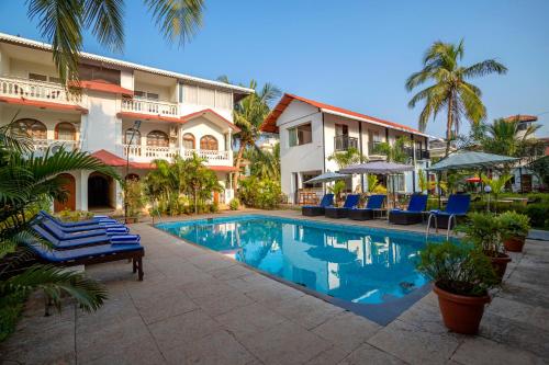 a resort with a swimming pool in front of a building at La Vaiencia Beach Resort, Morjim Beach in Morjim